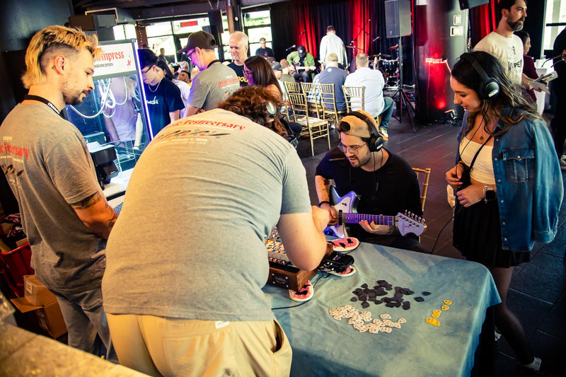 Players trying pedals on headphones at the Empress Effects table