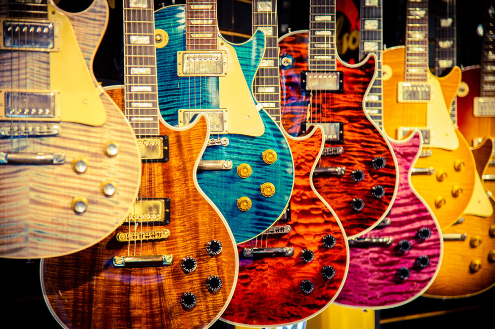 A row of Gibson Custom Les Pauls hanging on the wall at Lauzon Music, figured maple tops in blue, orange, pink and burst